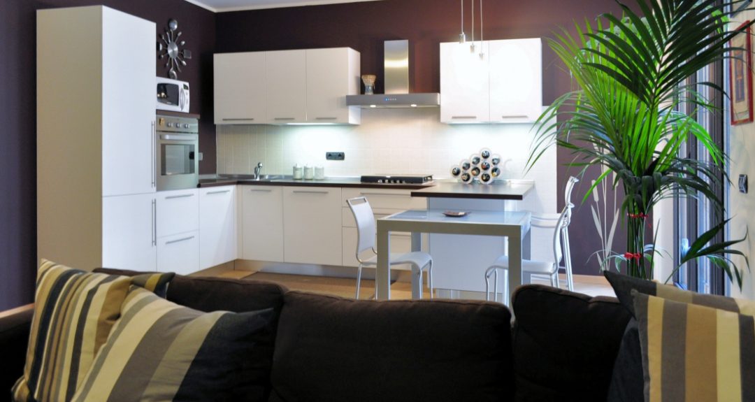 soggiorno living cucina bianca con penisola e parete cacao
