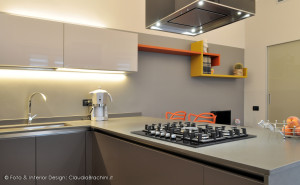 cucina grigio con particolari arancio, grande penisola con sgabelli