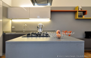 cucina grigio in vetro con particolari arancio, grande penisola con sgabelli