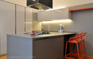 cucina grigia in vetro con particolari arancio grande penisola con sgabelli
