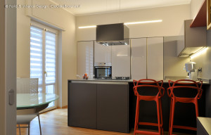 cucina grigia in vetro con particolari arancio grande penisola con sgabelli