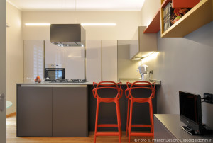 cucina grigia in vetro con particolari arancio grande penisola con sgabelli