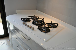 cucina laccata lucida bianca e grigio con elementi curvi, piano cottura in vetro bianco