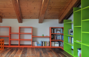 libreria a gradoni arancio e verde in mansarda